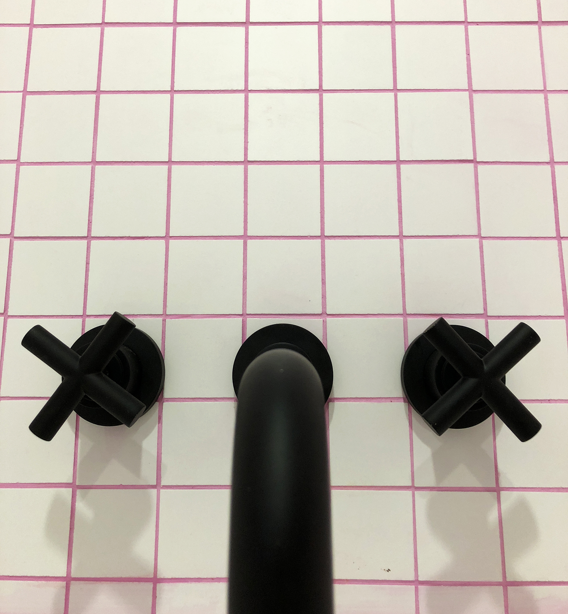 White bath tile with pink grout and matte black faucet