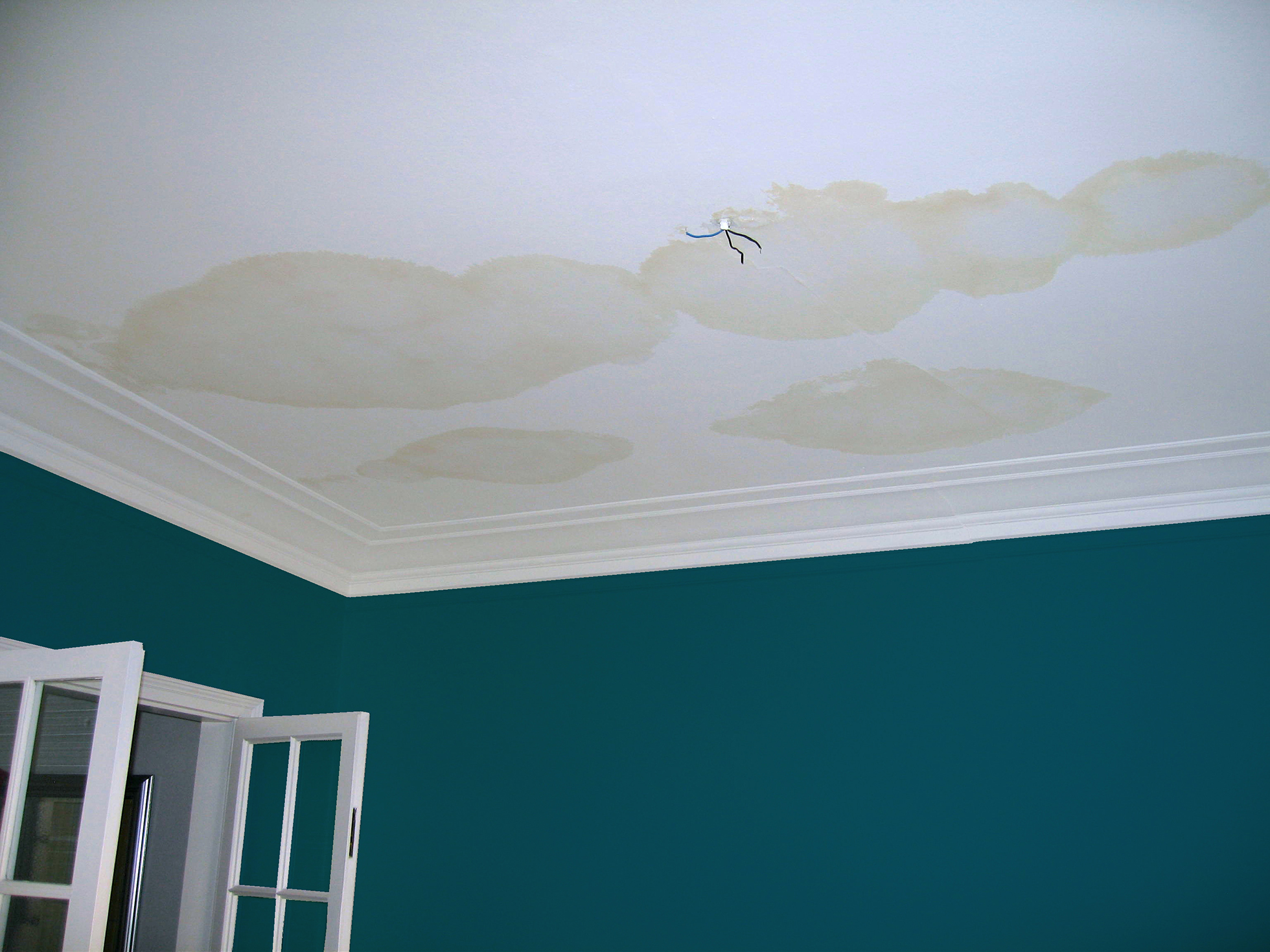 Dark blue room with white trim & water stains on the ceiling