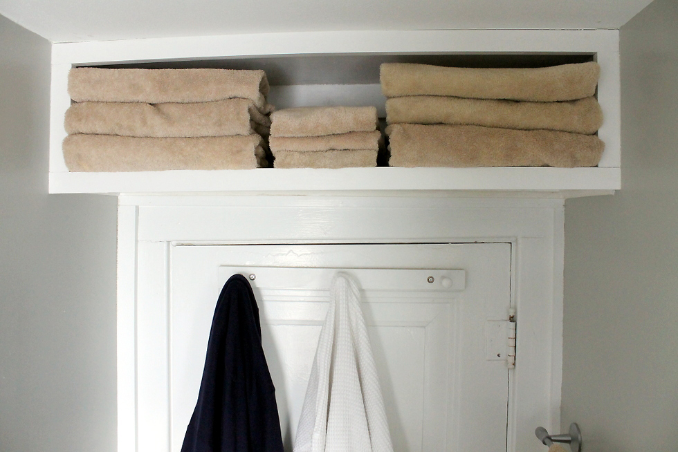Above-the-door shelf filled with towels in bathroom
