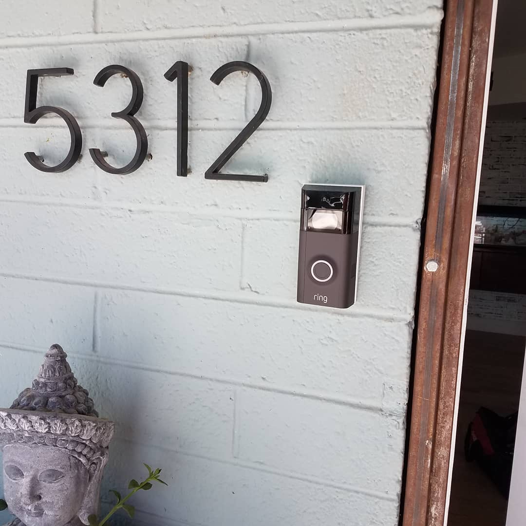 A video doorbell with a Buddha statue beside it