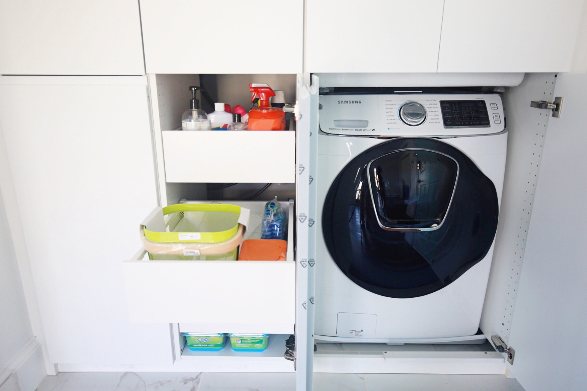 Cabinets opened to reveal washing machine and supplies