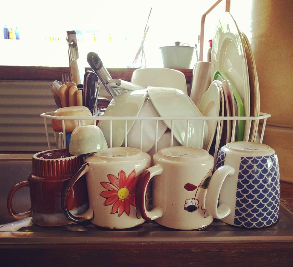 Assorted bowls, cups, and dishes stacked into dish dry rack