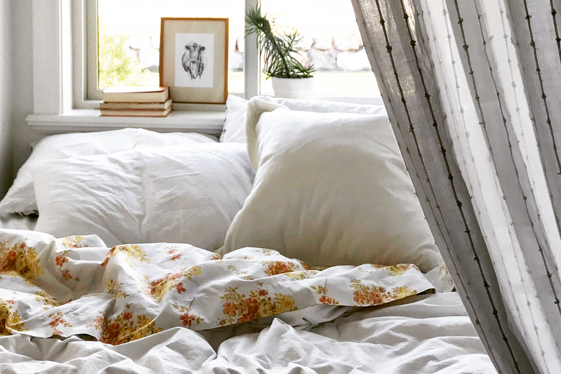 A bed with white sheets and a white bedspread by window
