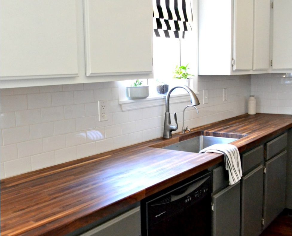 A kitchen with wood countertops and white and gray cabinets