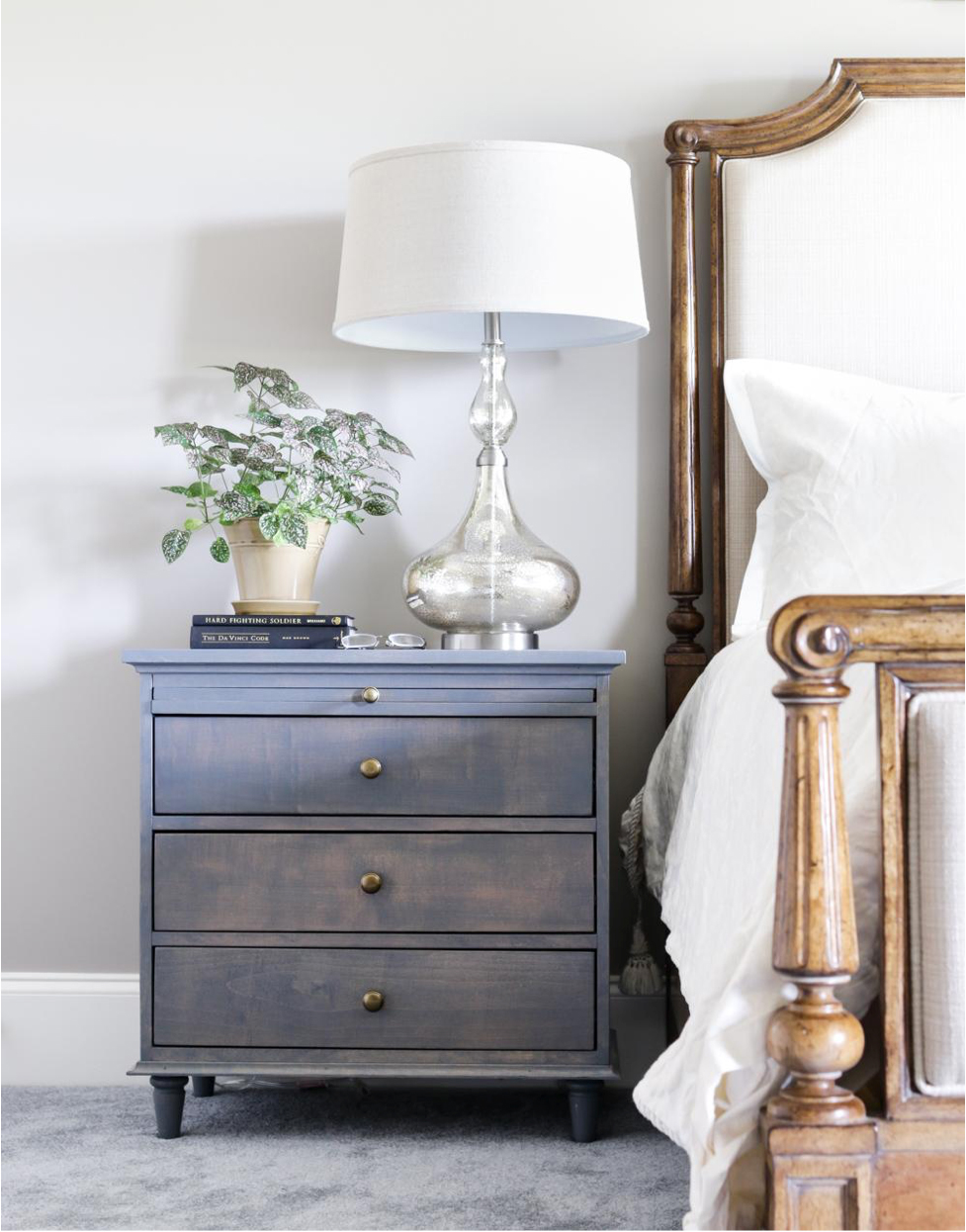Gray night stand next to a wood bed frame