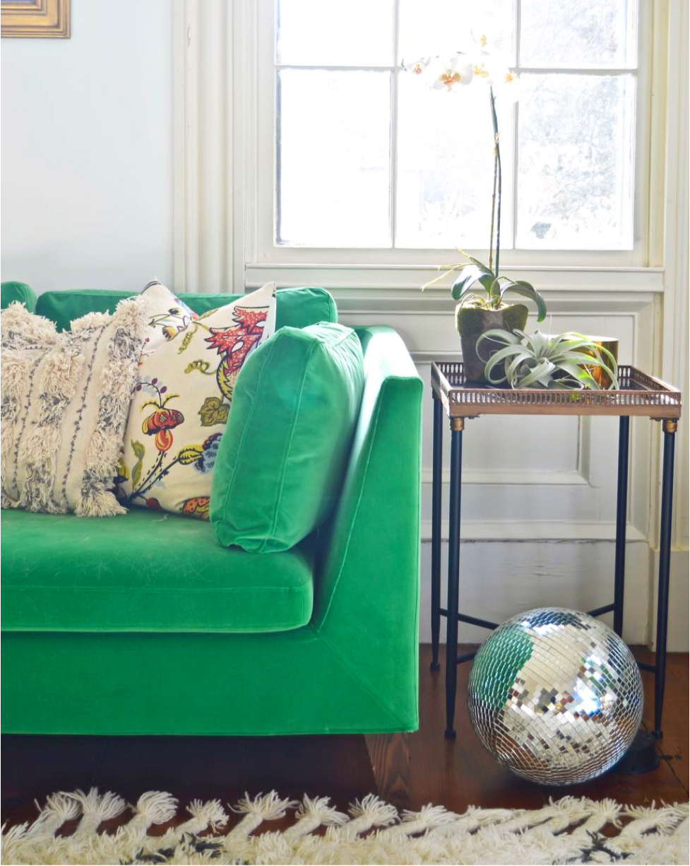 A living room with a bright green sofa and a disco ball