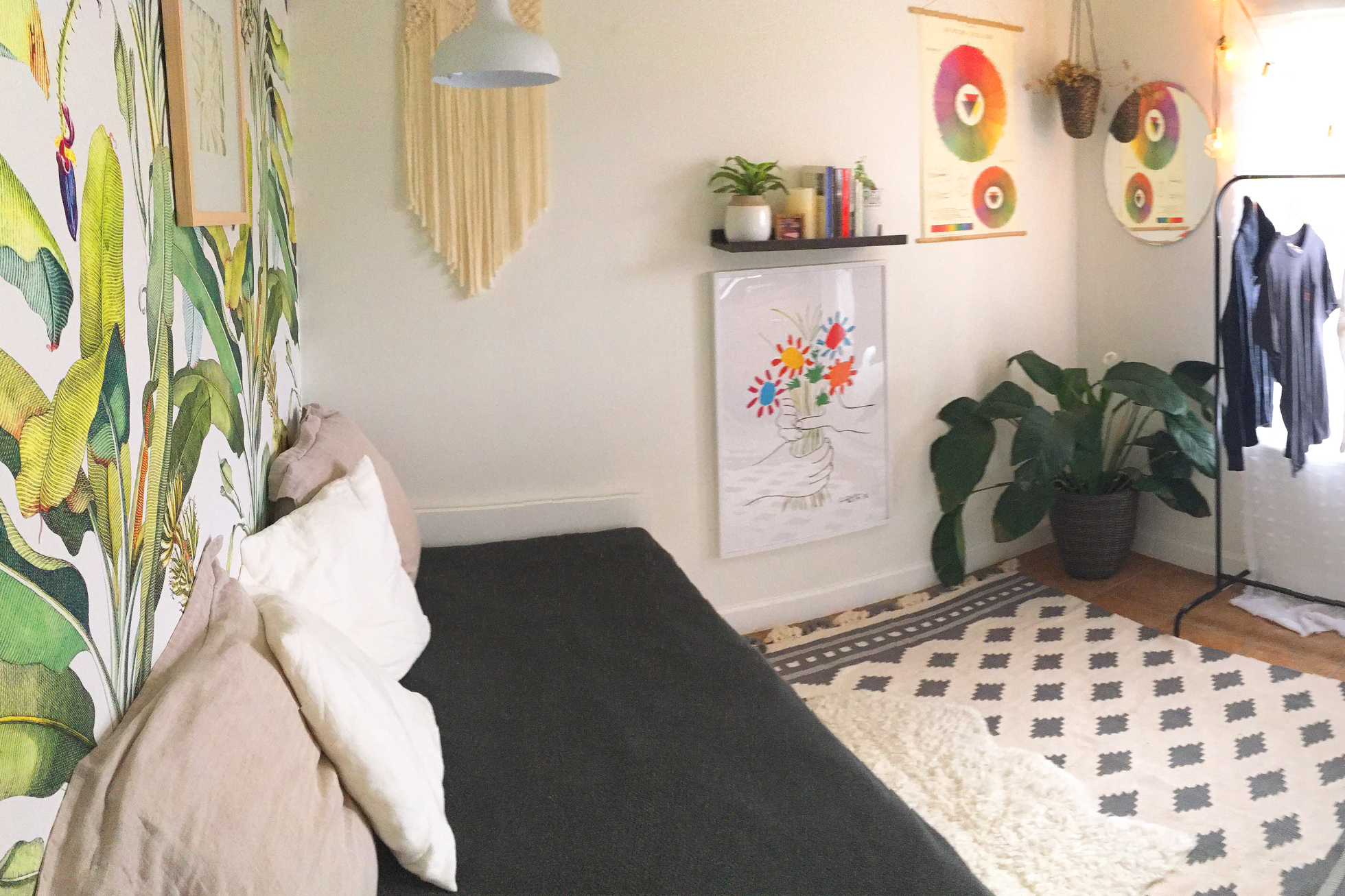 Bright room with tropical wallpaper and a black daybed