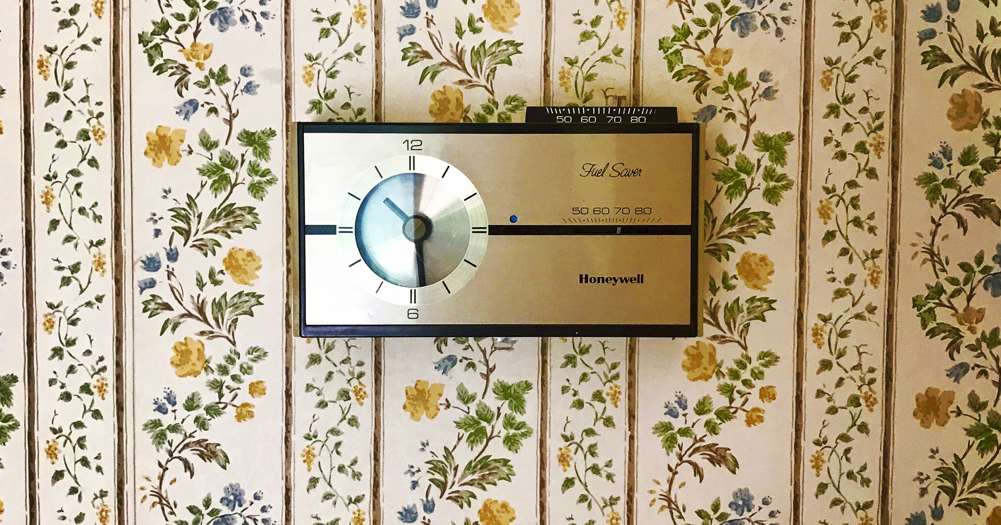 Vintage wallpaper with outdated thermostat in a home