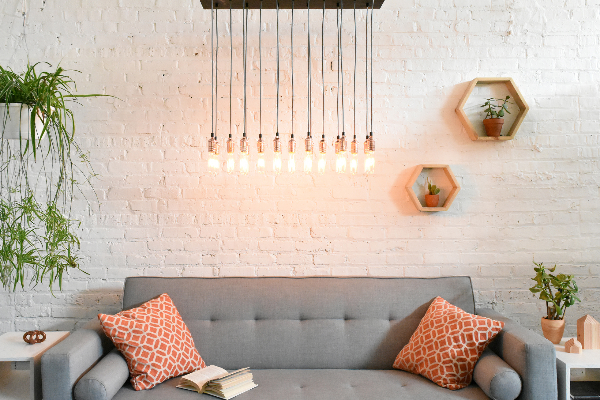 Wood chandelier with Edison bulbs over couch in living room