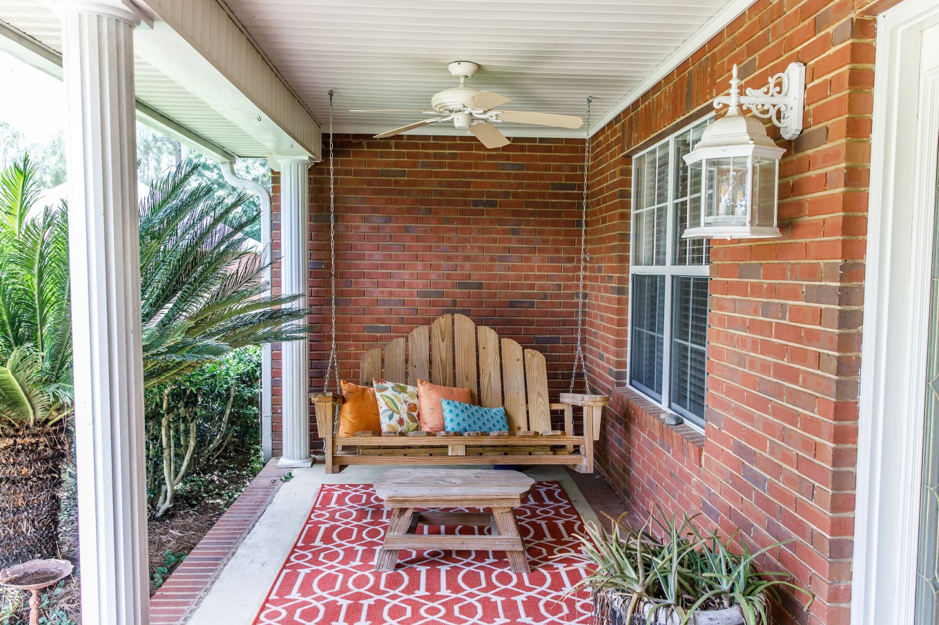 A porch swing in a nicely adorned outdoor space to allow for socializing.